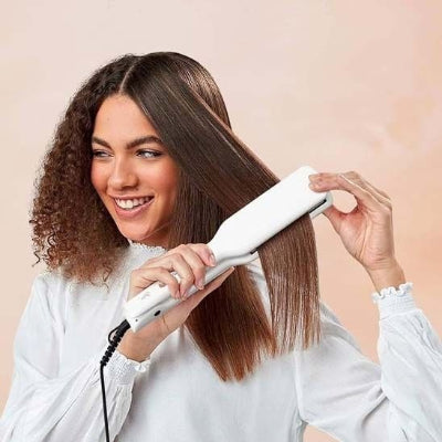 femme porte une chemise tient un lisseur cheveux