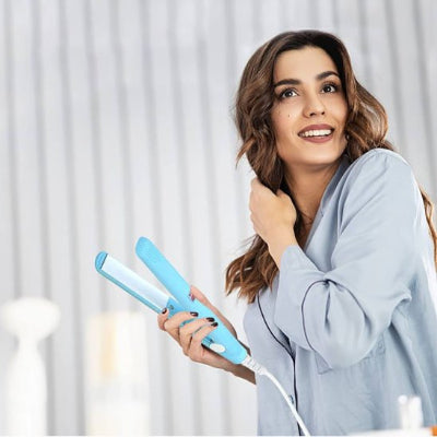 Jeune femme tient un fer a lisser bleu
