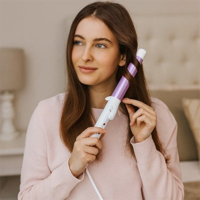 un femme utilise dans sa chambre un fer à friser