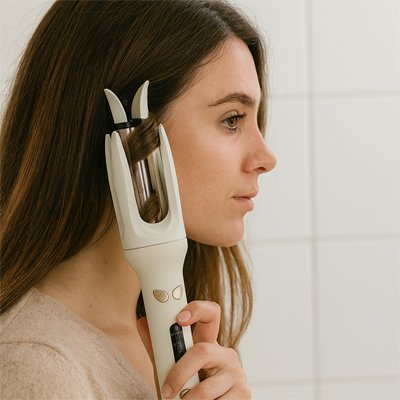 Une brune utilise un boucleur automatique jaune