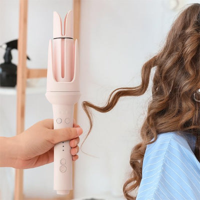 Une coiffeuse utilise un boucleur automatique 